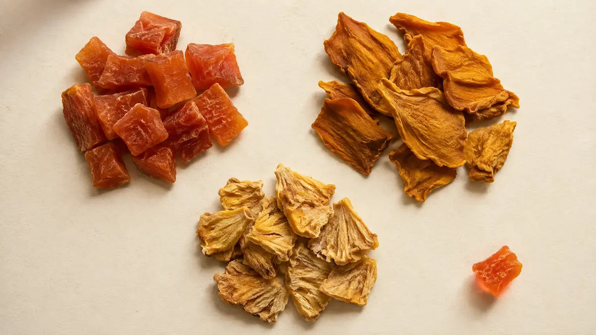 Chunks of dried papaya, mango and pineapple in muted natural colors on a cream background.